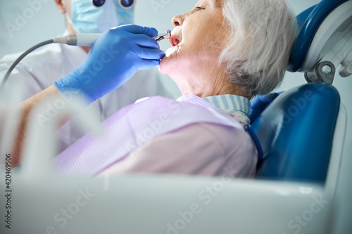 Fototapeta Dental specialist taking care of retired person tooth