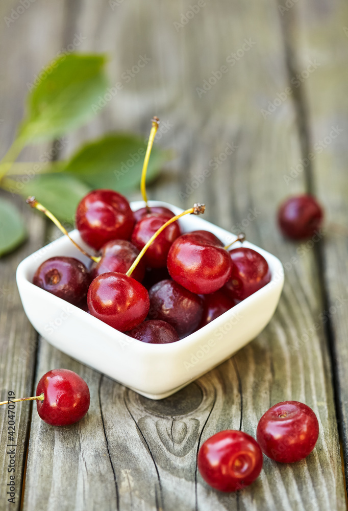 Cherry in a bowl on grey wooden old table. Ripe ripe cherries. Sweet red cherries. Cherry in a bowl on grey wooden old table. Ripe ripe cherries. Sweet red cherries.