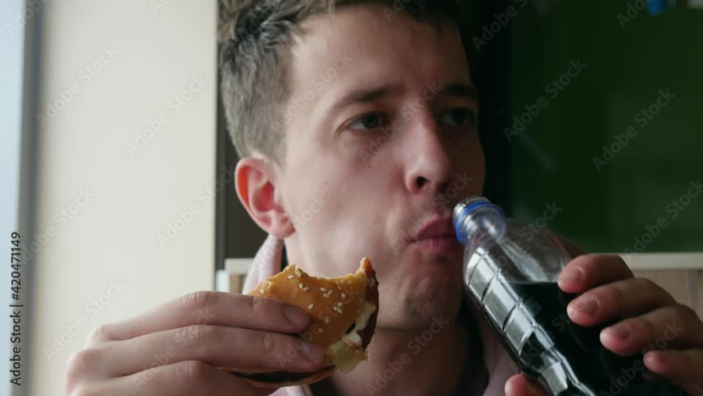 Young man appetizingly eats a juicy tasty hamburger. Junk food alternative, healthy fast food concept. Overweight problems Young man appetizingly eats a juicy tasty hamburger. Junk food alternative, healthy fast food concept. Overweight problems