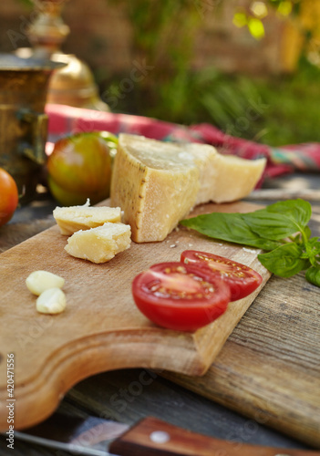 Tomatoes, garlic, basil and cheese parmigiano on an old authentic table. Fresh homemade ingredients