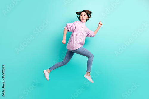 Full length photo of funky funny lady dressed purple pullover jumping running looking back empty space isolated teal color background