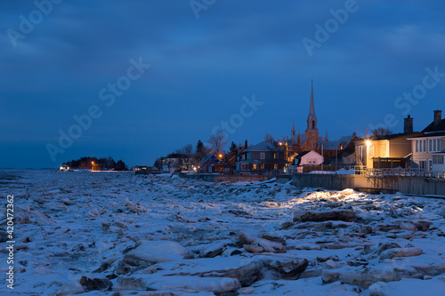 The St. Lawrence River’s icy coastline and Kamouraska village seen at dusk in winter, Quebec, Canada