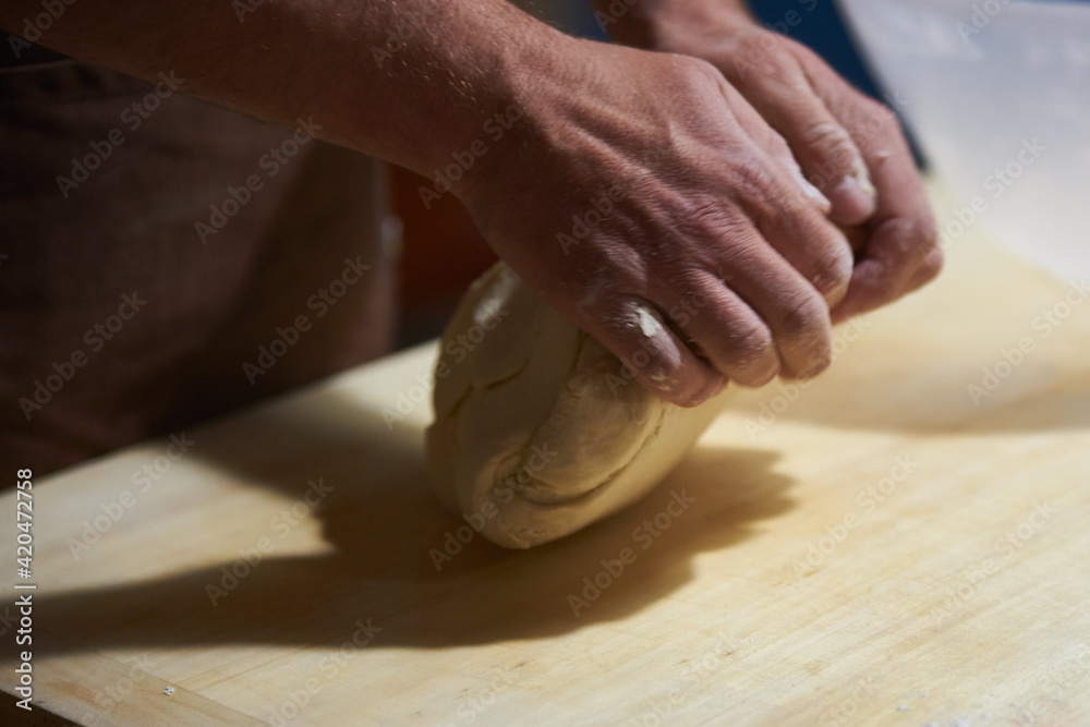 the cook kneads the dough in his hands on kitchen board