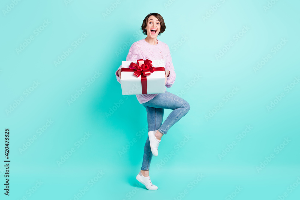 Full length photo of pretty excited young lady dressed purple pullover holding gift box isolated teal color background Full length photo of pretty excited young lady dressed purple pullover holding gift box isolated teal color background