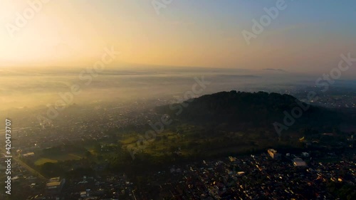 Mount Tidar on picturesque sunrise and Magelang city covered in fog, aerial view photo