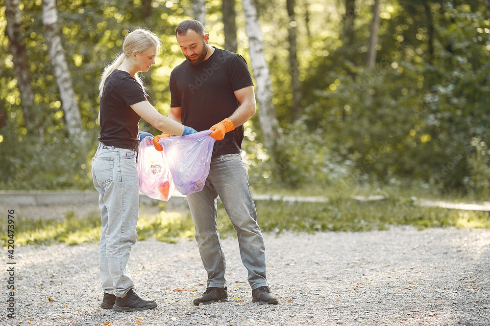 Fototapeta premium Couple collects garbage in garbage bags in park