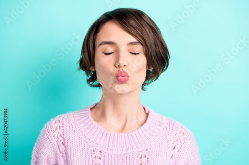 Photo of sweet adorable young lady dressed purple pullover closed eyes sending kiss isolated teal color background © deagreez