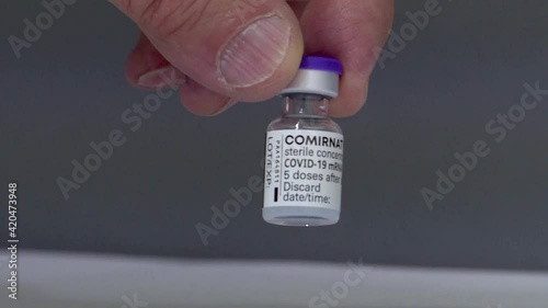 A hand holding a vile of covd 19 vaccination fluid. Cure to the pandemic photo