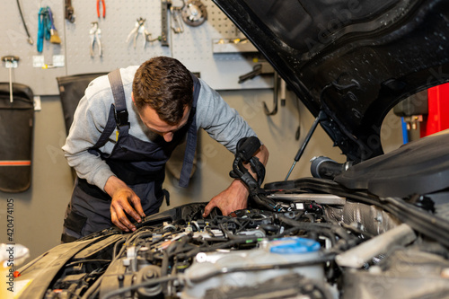 A professional car mechanic is changing an air filter, doing car service and maintenance of the vehicle. Oil and fuel filter changing. Service interval. 