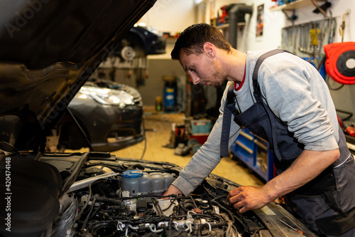 A professional car mechanic is changing an air filter, doing car service and maintenance of the vehicle. Oil and fuel filter changing. Service interval. 