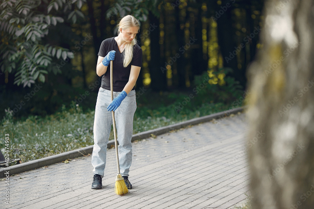 Woman collects leaves and cleans the park