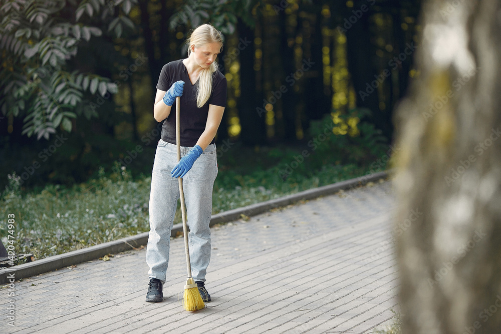 Woman collects leaves and cleans the park Woman collects leaves and cleans the park