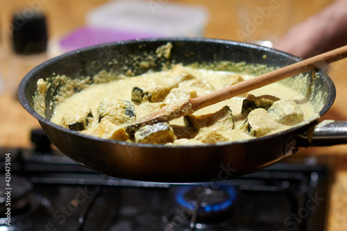 frying eggplant in sauce on a gas stove