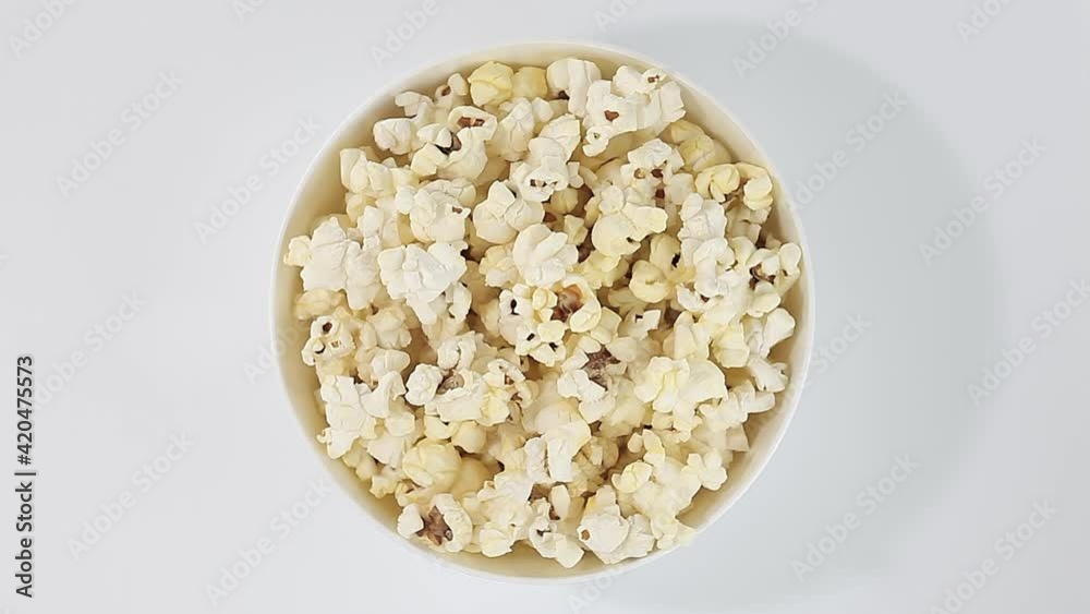 Popcorn corn, cooked in bowl rotation, turning clockwise on white background. Top view. Popcorn corn, cooked in bowl rotation, turning clockwise on white background. Top view.