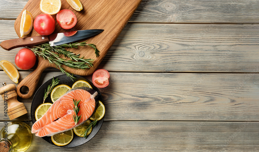 Salmon steak with ingredients for cooking on a wooden table with copy space. Salmon steak with ingredients for cooking on a wooden table with copy space.