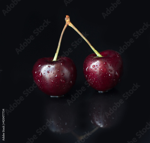 Close-up of cherry berries on a black background. Summer still life