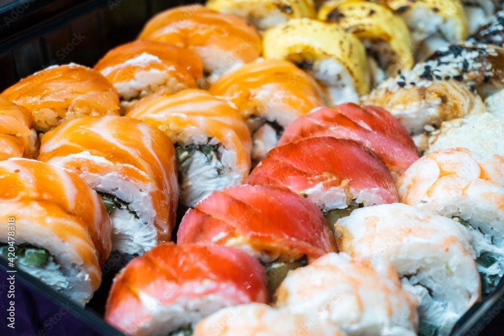 Large set of sushi rolls with shrimp, avocado, eel, chedar cheese, sesame seeds, caviar, tuna, nori, cucumber and cream cheese close-up, selective focus Large set of sushi rolls with shrimp, avocado, eel, chedar cheese, sesame seeds, caviar, tuna, nori, cucumber and cream cheese close-up, selective focus
