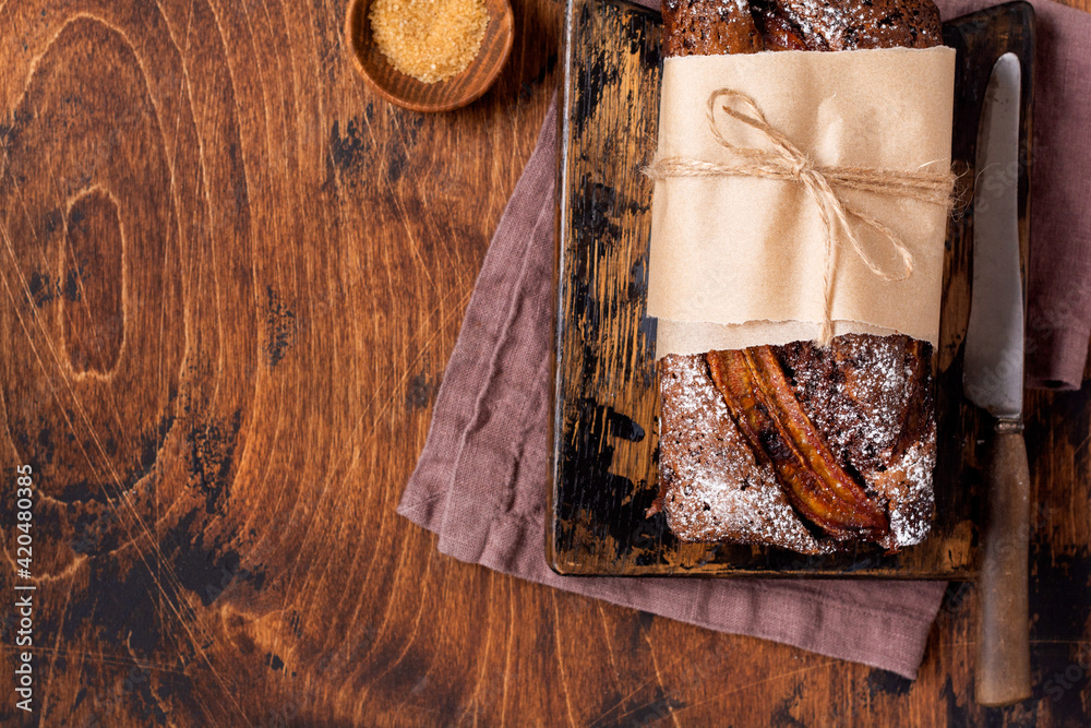 Banana bread with cinnamon crunch and sprinkled with icing sugar on light concrete background. Selective focus, space for text Banana bread with cinnamon crunch and sprinkled with icing sugar on light concrete background. Selective focus, space for text