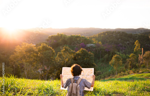 Traveler or adventurer holding a map with mountains and sunset in the background.