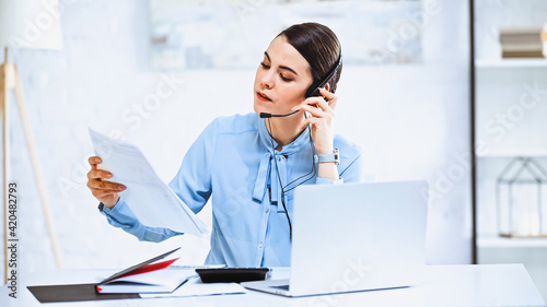 young call center operator looking at document while working in office