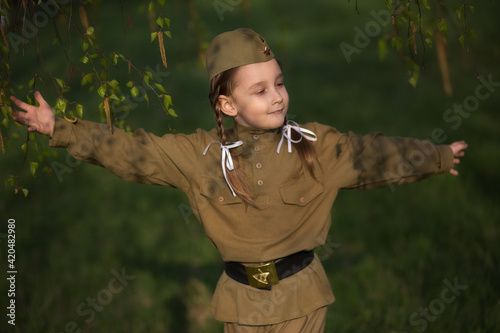 Cuadro en lienzo Portrait of a girl with pigtails dancing in a military uniform in the spring in