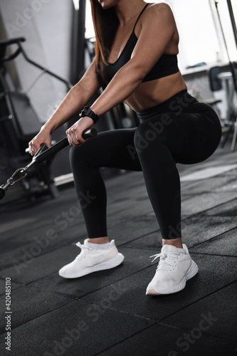 Vertical cropped shot of an athletic woman doing buttocks exercise in crossover gym machine