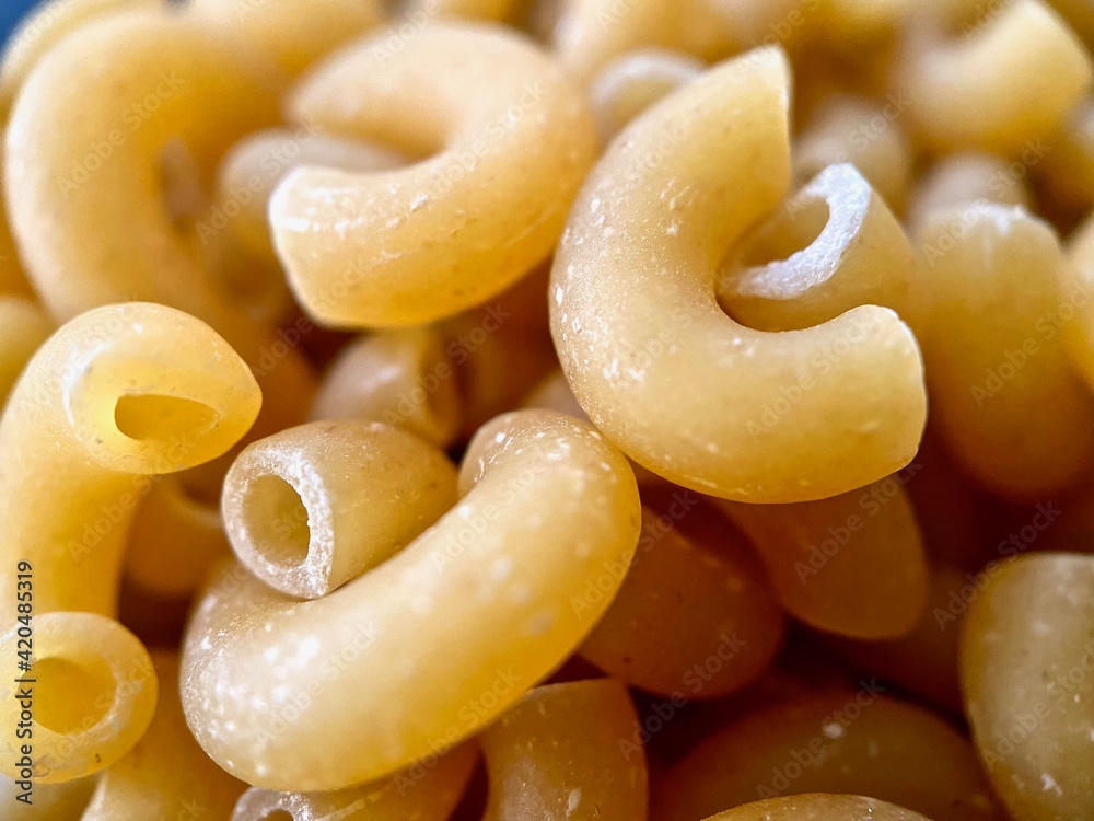 Foto Stock Closeup of dried elbow macaroni pasta. Dry pasta is made from  finely ground semolina flour or durum wheat and water that is mixed into a  paste, extruded and cut. Elbow