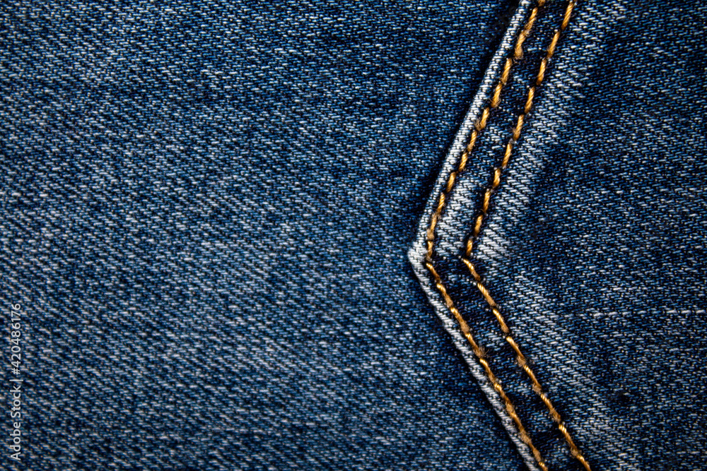 Background on the theme of denim clothing. Denim fabric with elements of seams. Background on the theme of denim clothing. Denim fabric with elements of seams.