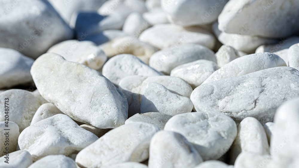 Close-up of light gray pebbles, smooth stones in a wrap-up plan as a background or wallpaper selected focus Close-up of light gray pebbles, smooth stones in a wrap-up plan as a background or wallpaper selected focus