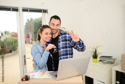 Young happy couple moving in new house and calling friends and family with laptop computer in their brand new apartment