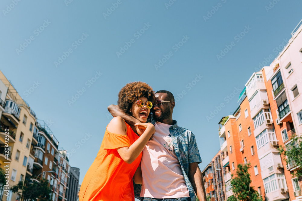 © MyMicrostock/Stocksy - Cheerful black couple hugging on street