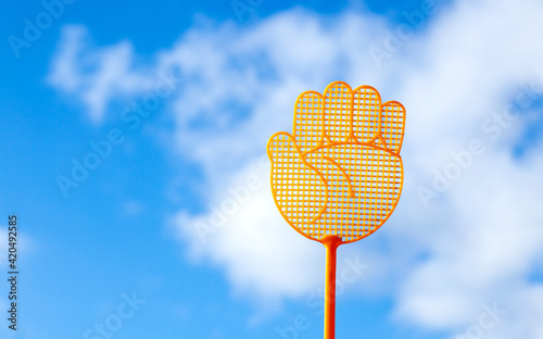 Raise your hand gesture symbol. Yellow plastic fly swatter on blue sky cloud background. Business and Environment concept. Save the World
