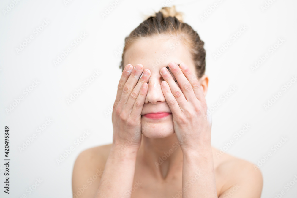 Happy Young Woman Applying Cream on Her Face, Studio Shot on White Background Happy Young Woman Applying Cream on Her Face, Studio Shot on White Background