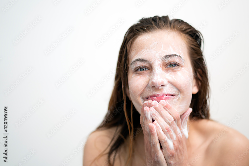 Happy Young Woman Washing her Face with Cream, Studio Shot on White Background Happy Young Woman Washing her Face with Cream, Studio Shot on White Background