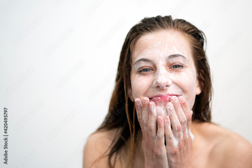 Happy Young Woman Washing her Face with Cream, Studio Shot on White Background Happy Young Woman Washing her Face with Cream, Studio Shot on White Background