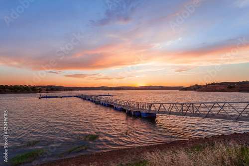 Alentejo travel destination in Portugal  Europe. Colorful landscape with pier on the Alqueva lake at sunset. Boat dock is a tourist attraction for holidays. Horizontal image with no people.