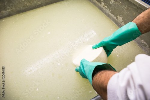Crop man washing cheese in brine