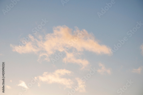 Morning clouds in sky highlighted by sunshine of the whispy white clouds floating against blue sky in early dawn.