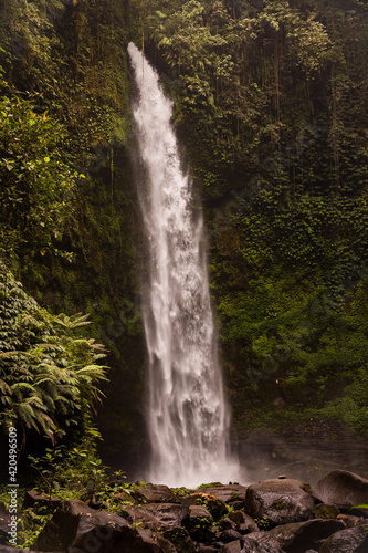 Waterfall landscape. Beautiful hidden waterfall in tropical rainforest. Foreground with big stones. Slow shutter speed  motion photography. Travel and adventure. Nung Nung waterfall  Bali
