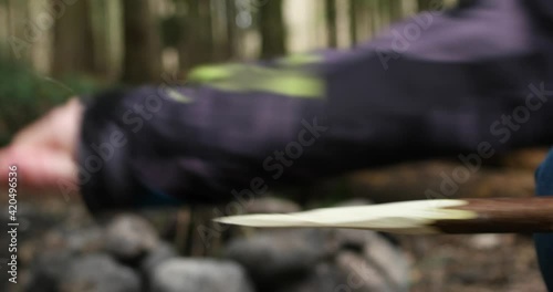 Caucasian male hand using a pocket knife to cut and sharpen a wooden stick skewer in the forest close up real time unrecognizable photo