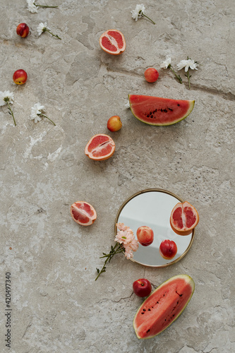 still life on the concrete floor, mirror, flowers, watermelon slices, grapefruit and peaches