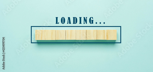 Table top view or flat lay of loading the progress bar with laying wooden cubes on blue paper background. Download waiting status.