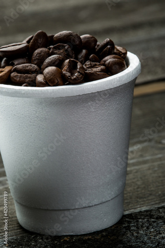 Chicchi di caffe dentro una tazzina, isolati su un tavolo di legno photo