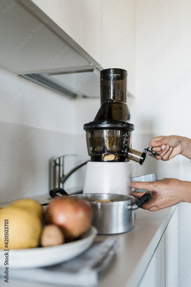 Woman preparing fresh juice for breakfast at home, using a centrifuge Woman preparing fresh juice for breakfast at home, using a centrifuge