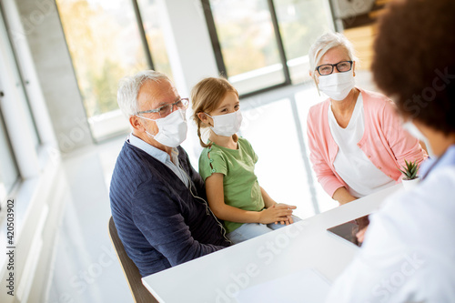 Senior couple with granddaughter at black female doctor
