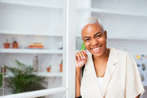 Happy ethnic businesswoman near window in office photo