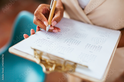 Crop ethnic businesswoman making notes in calendar
