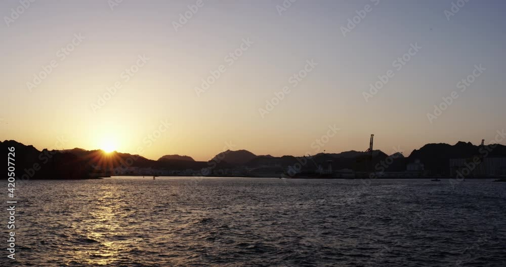 Sunset across the ocean, the hills and mountains of Muscat, Oman, wide shot Sunset across the ocean, the hills and mountains of Muscat, Oman, wide shot