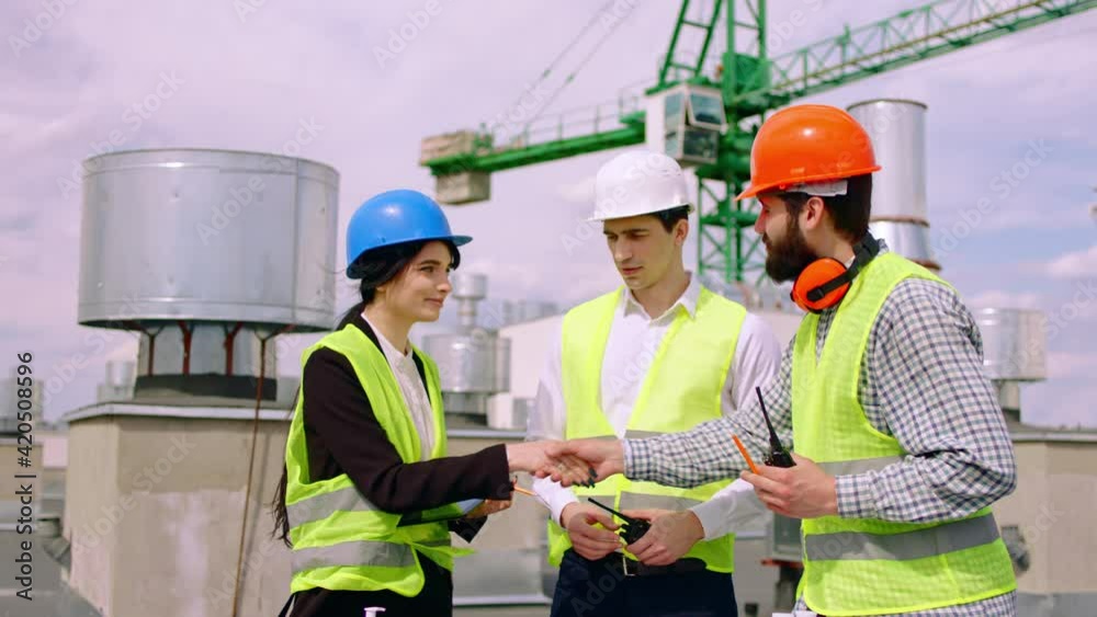 Charismatic businessman and his construction team engineer lady and architect man with a safety helmets on the top of building meeting each other to discussing about the plan of construction. 4k Charismatic businessman and his construction team engineer lady and architect man with a safety helmets on the top of building meeting each other to discussing about the plan of construction. 4k