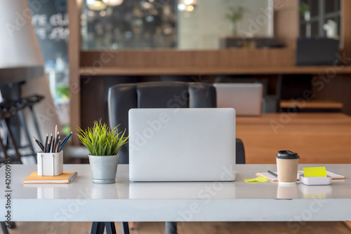 Front view of the laptop and the working devices placed on the table at the office.